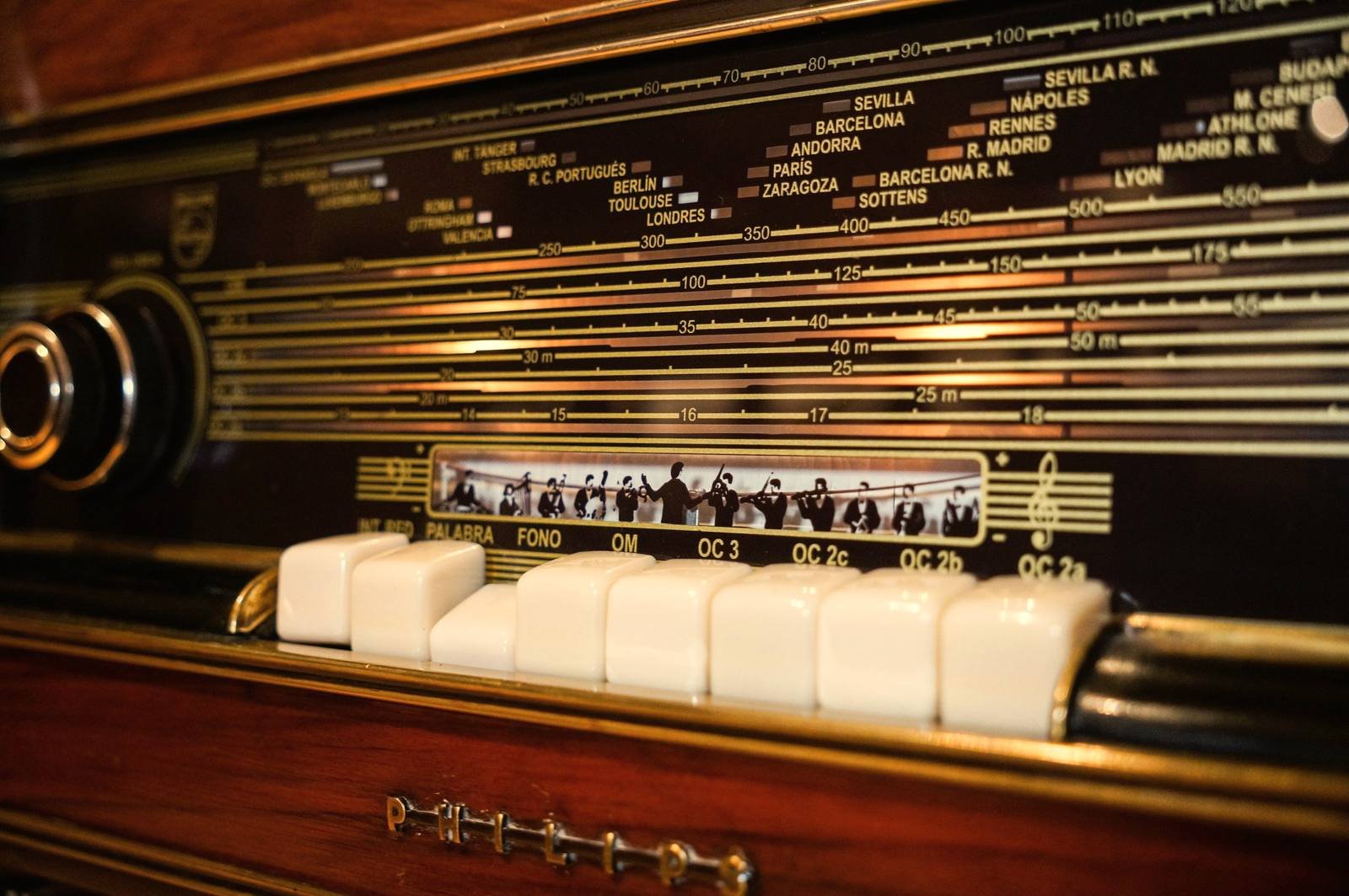 Primer plano del dial iluminado de una radio antigua de madera, con los nombres de las emisoras
